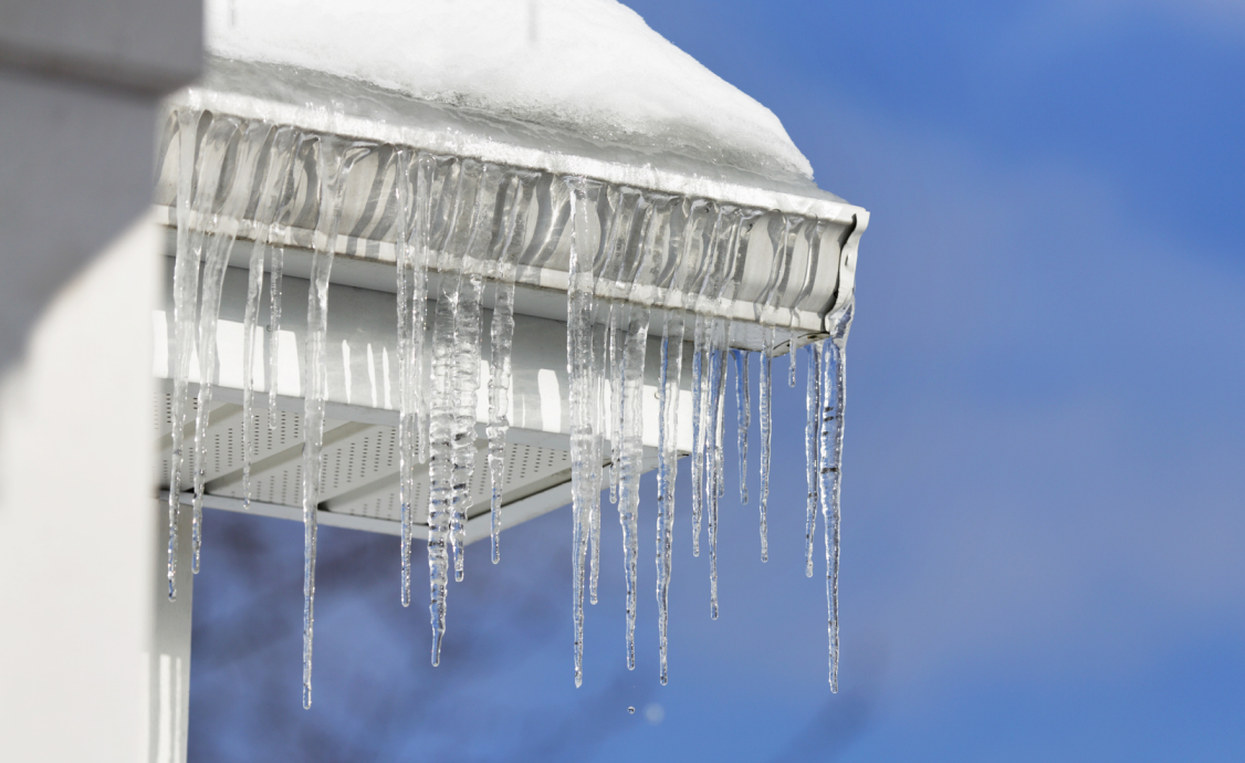 Ice dam forming on a roof gutter replacement system in Delaware winter conditions